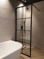 a bathroom with a tub and a glass shower at Vakantiehuis Onverbloemd in Tielt