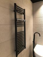 a bathroom with a black towel rack on the wall at Vakantiehuis Onverbloemd in Tielt