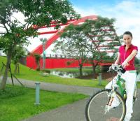 a girl riding a bike in a park with a roller coaster at Dongshan River Resort Farm in Wujie