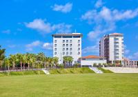 a white building in front of a green field at Hotel Yugaf Inn Okinawa in Nago