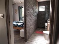 a bathroom with a brick wall and a bedroom at kokopoirier in Terre-de-Haut