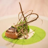 a piece of meat on a green plate with greens at Best Western Premier Hotel de la Cite Royale in Loches