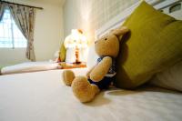a teddy bear sitting on a bed next to a pillow at 洄瀾雅舍民宿-近火車站-東大門夜市附近 in Hualien City