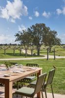 uma mesa de madeira com cadeiras em um campo em Hotel Terraverda at Empordà Golf Resort em Torroella de Montgrí