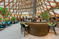 a bar in a restaurant with chairs and a person at PARKROYAL COLLECTION Marina Bay, Singapore in Singapore