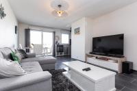 ein Wohnzimmer mit einem Sofa und einem Flachbild-TV in der Unterkunft Appartement tout confort - Pau Nord in Pau