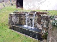 a water fountain in a stone wall in a yard at Gite au pied du mont Lozère 2 in Mas-dʼOrcières
