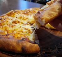 a person holding a slice of cheese pizza at Hotel & Restaurant Aragwi in Salzwedel