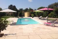 a swimming pool with two umbrellas and two chairs and a pool at Suite spacieuse avec accès piscine in Ghisonaccia