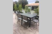 a black dining table and chairs on a patio at Suite spacieuse avec accès piscine in Ghisonaccia