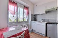 a kitchen with white cabinets and a table with a red table cloth at Appartement 2 pièces plein de charmes - Caroline in Valentigney