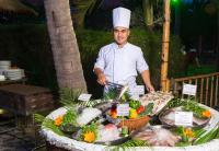 um chef ao lado de uma mesa de comida em Muine Century Beach Resort & Spa em Mui Ne