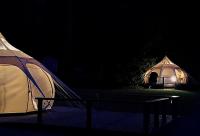 two tents are lit up in the dark at Glamping at Camping La Source in Saint-Pierre-dʼArgençon