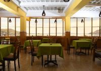 プーノにあるHotel Qalasayaの緑のテーブルと椅子、窓のあるレストラン