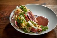 a white plate of food on a wooden table at Pendry Chicago in Chicago