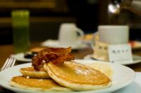 a plate of pancakes with bacon and oranges on a table at KALI Centro Mexico City in Mexico City