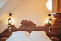 a bed with two pillows and two lights on a brick wall at Le Saltimbanque - Auberge du Moulin in Eaucourt-sur-Somme