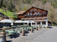 Un restaurante con mesas y sombrillas frente a un edificio. en Hotel Restaurant Waldrand, Isenfluh, en Isenfluh