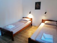 two beds in a room with white walls and wooden floors at Nikolića kuća in Mitrovac