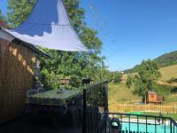 a patio with a table and a white umbrella at Gîte Tanagra : Maison avec piscine et vue exceptionnelle in Roquefort-les-Cascades