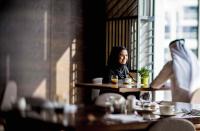 a woman sitting at a table in a restaurant at InterContinental Dubai Marina by IHG in Dubai
