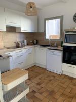 a kitchen with white cabinets and a wooden floor at Appartement la corde a linge Gruissan village avec terrasses in Gruissan