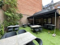a patio with tables and chairs and a black umbrella at Hotel Guzy in Lier