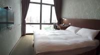 a bedroom with a large white bed in front of a window at The Galerie Hotel in Taichung