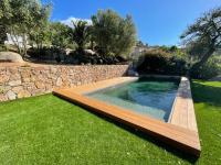 a swimming pool in a yard next to a stone wall at Bel appartement dans hameau calme in Bonifacio