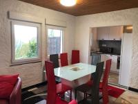 a dining room with a white table and red chairs at LA PETITE MESANGE in Dabo