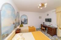 a bedroom with two beds and a desk and a television at Casa Teresa in Positano