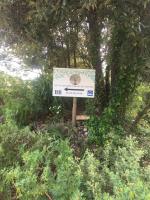 a sign in the middle of a field with trees at chambre d’hôtes des oliviers in La Roque-sur-Cèze