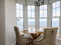 a dining room with a table and chairs and windows at Sennen Heights in Sennen Cove