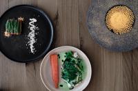 una mesa con dos platos de comida y un bol de verduras en Haller Suites & Restaurant, en Bresanona