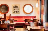 um restaurante com mesas e cadeiras e um banco vermelho em Das Ebertor - Hotel & Hostel em Boppard