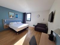 ein Schlafzimmer mit einem Bett, einem Sofa und einem Stuhl in der Unterkunft Kyriad Bordeaux Nord Sainte Eulalie in Sainte-Eulalie