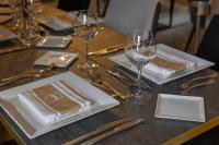 Una mesa de madera con vasos, platos y cubiertos. en Ferme de la Rançonnière - Hôtel & Restaurant, en Crépon