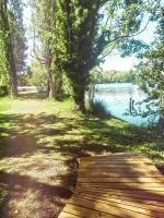 a wooden path next to a lake with trees at Hôtel L&#39;ile Du Saussay in Itteville