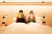 un hombre y una mujer acostados en la cama leyendo libros en Zero Box Lodge Porto, en Oporto