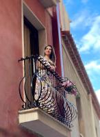 a woman looking out of a balcony with flowers at Domus Cuseni in Taormina
