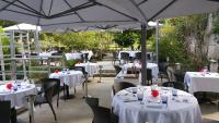 BassacにあるLogis Hôtel Restaurant L'Essilleの白いテーブルと椅子、パラソルが備わるレストラン