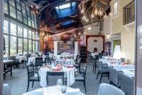 BassacにあるLogis Hôtel Restaurant L'Essilleの白いテーブルと椅子と窓のあるレストラン