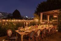 Una mesa larga con sillas y luces por la noche. en Petit Ermitage, en Los Ángeles