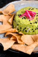 Un plato con salsa verde con patatas fritas y cebollas. en BOURBON HOSTAL, en Juayúa