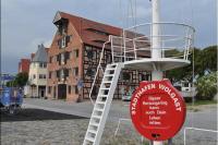 a red sign in front of a house with a ladder at Der Speicher in Wolgast