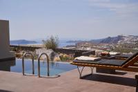 a pool with a table and a bench next to a pool at Apikia Santorini in Pirgos