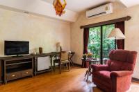 a living room with a television and a chair at Yaang Come Village Hotel in Chiang Mai