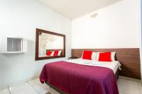 Un dormitorio con una cama con almohadas rojas y un espejo. en Hotel Cambará, en Osasco