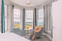 a bedroom with a bed and chairs and windows at Oceanside Lifestyle Hotel in Newquay
