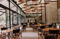 Un restaurante con mesas y sillas de madera y ventanas. en Rodavento Boutique Hotel & Spa, en Valle de Bravo